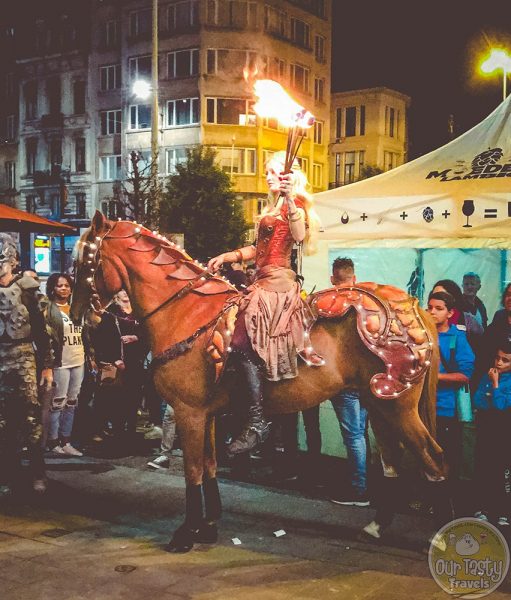 A woman carrying a torch rides a horse at Zwanze Day 2017