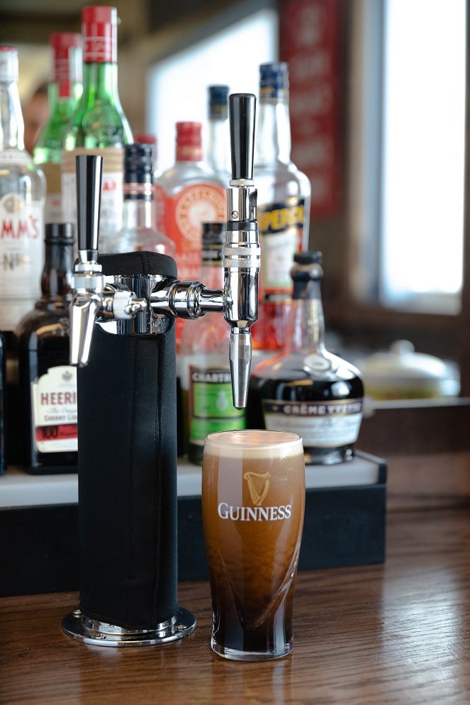 A freshly poured Guinness beer sits under a stout beer faucet.